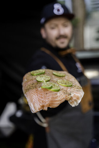 Mann hält Fisch zum Grillen @ 