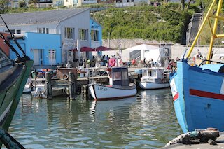 Kleine Boote an Holzstegen vor bunten Hafenfassaden an einem sonnigen Hafenbecken @ 
