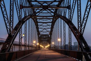 Beleuchtete Stahlbogenbrücke mit Laterneleuchten im blauen Abendlicht @ 