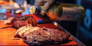 Gegrilltes Fleisch wird beim BBQ-Catering in Leipzig mit Öl verfeinert @ 